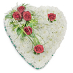 A finely crafted heart-shaped memorial piece sits against a clean white backdrop, its surface a soft, cloud-like cushion of hundreds of small, pristine white chrysanthemums carefully set to form a seamless, textural heart. The chrysanthemums' many-petalled faces read as purity and quiet, their matte white catching a cool, overhead light that throws gentle shadows into the dense arrangement and emphasizes the rounded form. From the upper left a graceful diagonal spray of deep crimson roses unfurls: three roses clustered together amid glossy ruscus and delicate, fern-like fronds, the foliage lending a dark, comforting green that cradles the blooms. Two more single roses punctuate the design - one near the upper right curve and one at the lower point - each given a few spare green accents and slender bear-grass blades that arc softly, creating movement across the stillness of the white field. A narrow emerald satin ribbon follows the heart's edge, its fine sheen defining the silhouette and providing a solemn, finished border. The scent is implied: the faint, tea-like perfume of red roses balanced by the clean, green top notes of fresh foliage. The composition reads as dignified and intimate, an arrangement intended to convey respect, enduring love, and remembrance at a funeral or memorial service. As a local florist's design, it feels at home arriving for services near Archway Station, Whittington Hospital chapels, or quiet family gatherings on Archway Road, available for thoughtful delivery across Archway, Upper Holloway and neighbouring Tufnell Park when you need a gentle, traditional tribute.